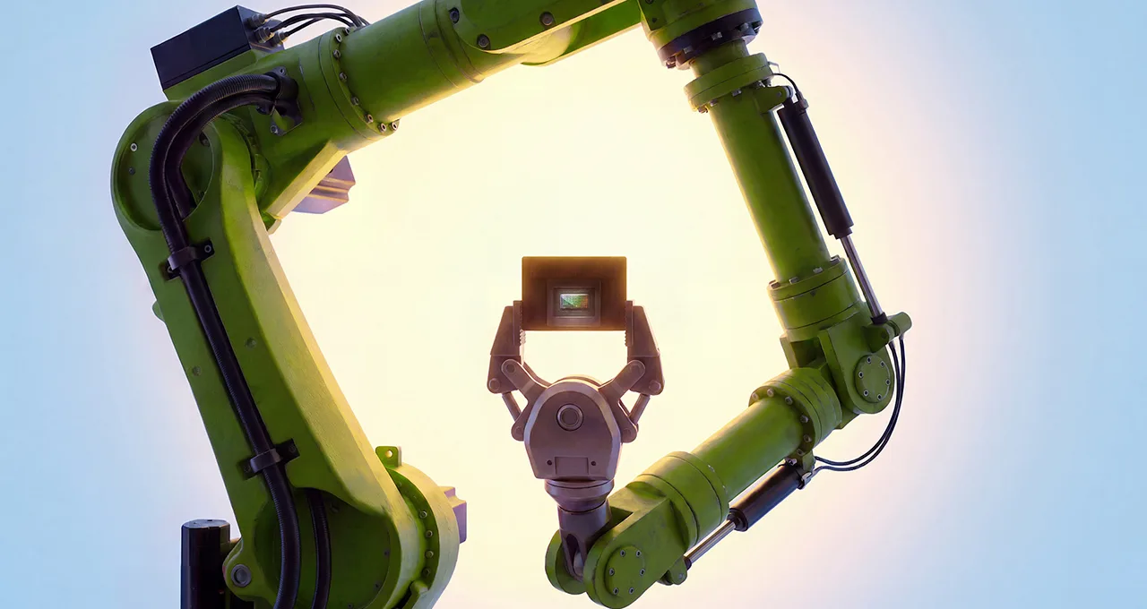 Robotic arm holding a processor chip, framed by a second robotic arm
